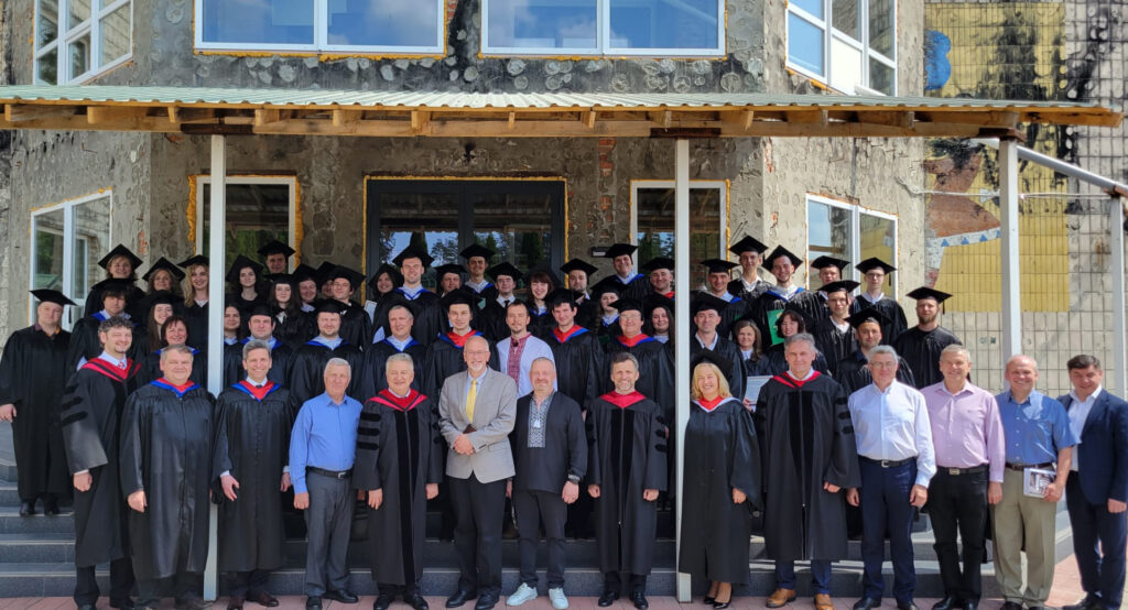 Irpen Biblical Seminary graduates stand in front of the damaged seminary building.