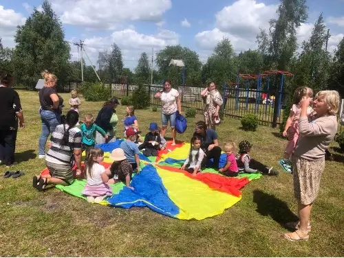 Kids and parents sitting on a rug at a playground