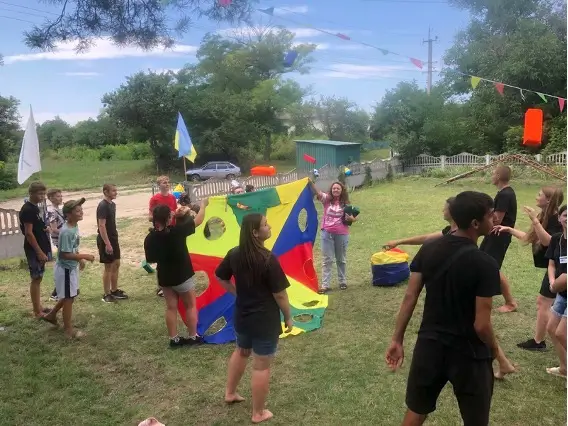 Kids holding a multicolored blanket